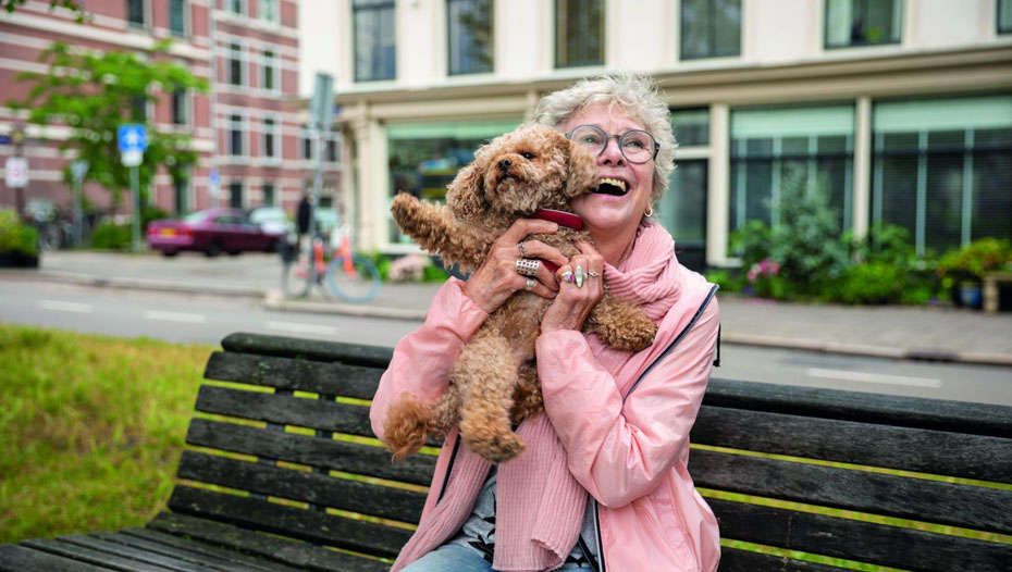 Dame løfter opp hund på parkbenk